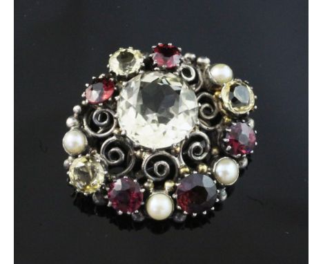 An early 20th century Arts & Crafts silver, citrine, garnet and split pearl set clip. of oval form, with pierced whorl decora