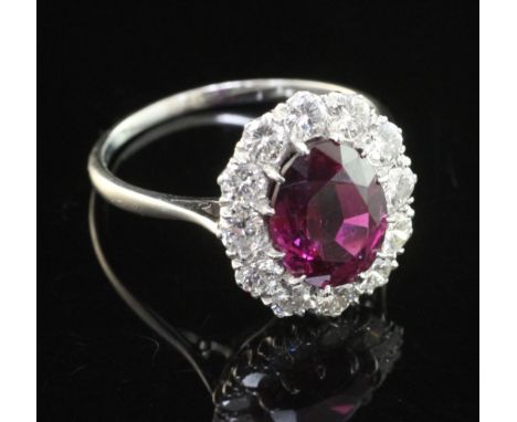 An 18ct white gold and platinum, ruby and diamond cluster ring, of oval form, the central oval cut ruby weighing 3.78ct with 