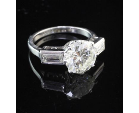 An early to mid 20th century platinum and single stone diamond ring with baguette cut diamond set shoulders, the central ston