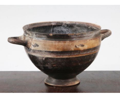 A Greek black slip decorated skyphos, Apulia, c.4th century BC, 22.5cm, broken and re-assembled