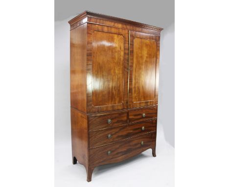 A George III mahogany linen press, with two doors enclosing five sliding trays above two short and two long drawers, on splay
