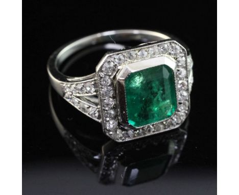 A white gold, emerald and diamond set octagonal ring, the central emerald weighing 1.94ct, with diamond set border and pierce