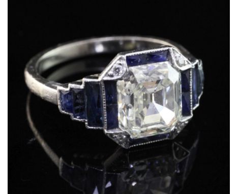 An Art Deco platinum single stone diamond and sapphire octagonal dress ring, with central emerald cut diamond and graduated s