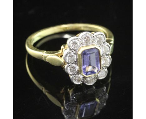 A modern 18ct gold, tanzanite and diamond cluster ring, of oval form, set with emerald cut tanzanite and ten stone diamond bo