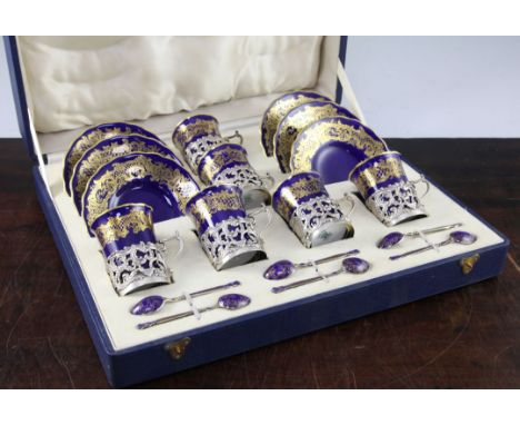 A cased Coalport silver mounted coffee set, 1930's, the six coffee cups and saucers with gilt scrollwork borders on a cobalt 
