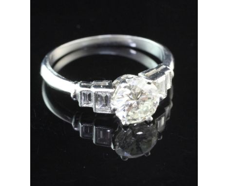 A platinum and single stone diamond ring with graduated emerald cut diamond set shoulders, the central stone weighing approxi