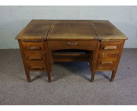 An oak typists desk, early 20th century, the rectangular top with folding and recessed typewriter platform, flanked by an arr