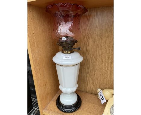A LARGE GLASS OIL LAMP WITH RED GLASS SHADE 