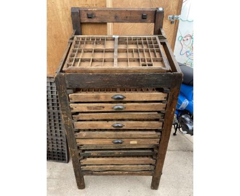 A VINTAGE WOODEN PRINTERS WORK STATION ENCLOSING TEN DRAWERS AND A SLOPPED WORK TOP WHICH ALSO CONTAINS A PRINTERS TRAY 