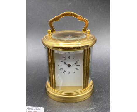 An oval travelling clock with bevelled glass panels, swing handle, 4" high