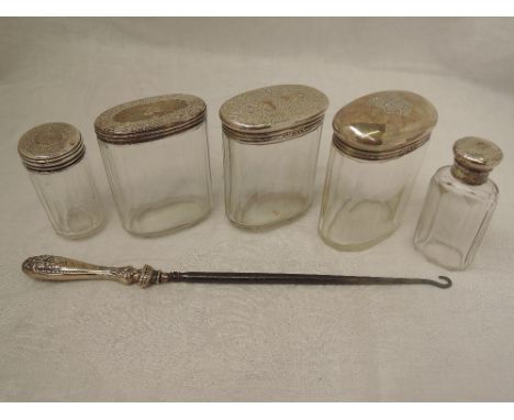 Five cut glass dressing table pots and bottles having HM silver lids and an HM silver handled button hook