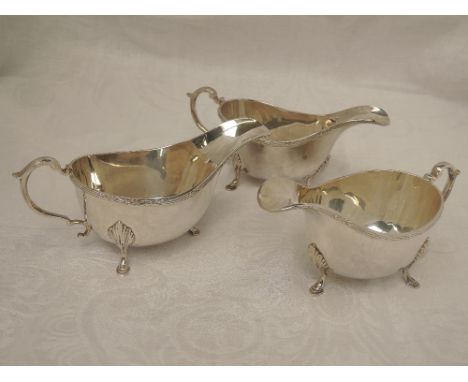 A trio of silver sauce boats having reed and sprig decoration to rim, trefoil hoof feet and moulded handles, London 1957, S J