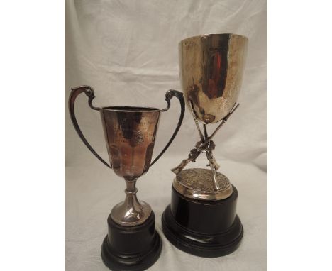 A silver trophy cup having a trio of shotgun rifles modelled as the stem with plain cup above with traditional wooden base, B