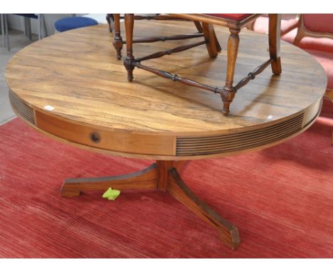 A mid 20th century rosewood drum table, the top having 4 drawers with reeded panels, raised on a turned column and tripod bas