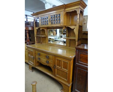 An impressive Arts and Crafts light oak mirror-back sideboard, the mirror-back fitted with open shelves and bottle glass pane