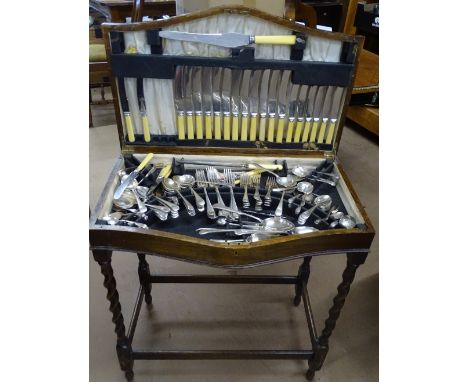 A canteen of Sheffield plate cutlery for 12 people including carving set, in floor standing oak cabinet raised on barley twis