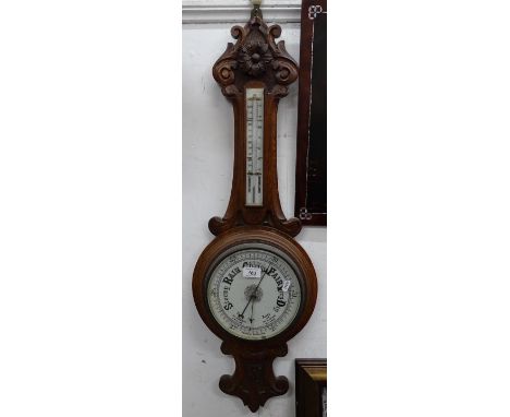A carved oak-cased aneroid barometer