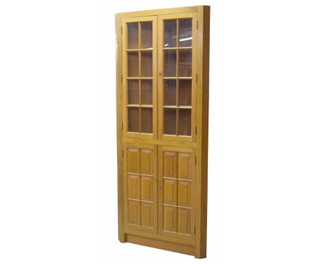 Modern light oak corner cupboard, the upper glazed cupboard doors enclosing shelved interior, the lower solid panelled doors 