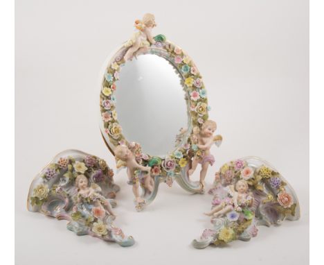 Dresden china table mirror, decorated with cherubs and flowers, 32cm, easel back, and two very similar Dresden china brackets