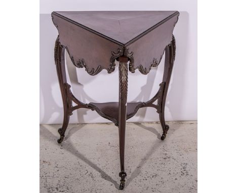 An Edwardian mahogany occasional table, triangular top with three leaves, carved edge, carved cabriole legs, joined by a shel