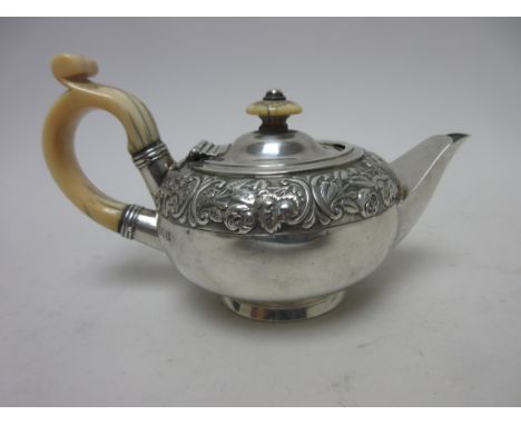 An Edward VII silver Bachelor's Teapot with floral and scroll embossed frieze, ivory scroll handle and finial, London 1909, m