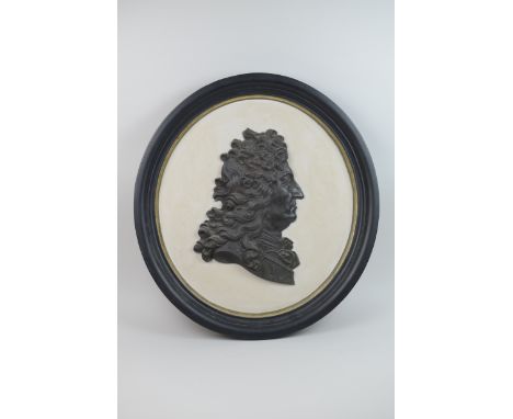 A black relief plaque, Portrait in profile in an ebonised frame, 20 inches diameter