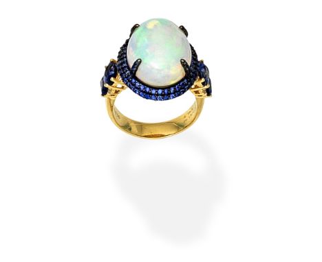 OPAL, SAPPHIRE AND DIAMOND RINGThe opal cabochon within a double surround of circular-cut  sapphires, between shoulders set w