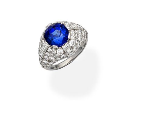 SYNTHETIC SAPPHIRE AND DIAMOND DRESS RINGThe circular-cut synthetic sapphire, within a bombé mount of brilliant and baguette-