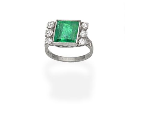 EMERALD AND DIAMOND RINGThe step-cut emerald between trios of brilliant-cut diamonds, the bifurcated shoulders set with singl