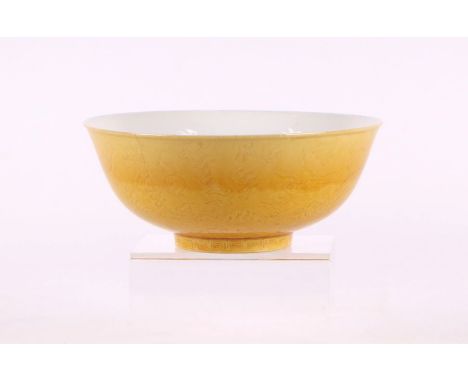 A Chinese footed bowl with sgraffito decoration depicting dragons chasing a flaming pearl, on a yellow ground, six character 