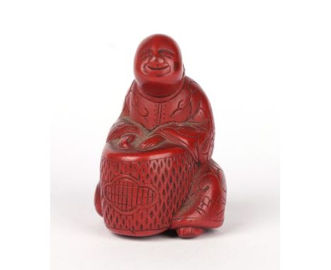 A 19th century Japanese red cinnabar lacquer netsuke in the form of a seated man playing a drum, 3.5cms high.