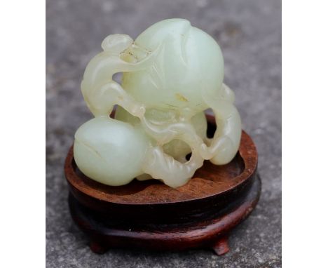 A Chinese jade / hardstone group depicting monkeys climbing on fruit, on a hardwood stand, 5cms high.