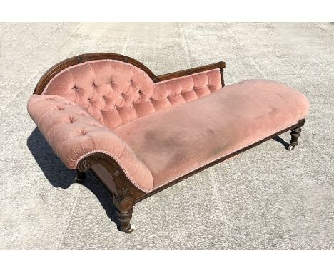 A Victorian upholstered button back chaise longue with carved walnut show wood.