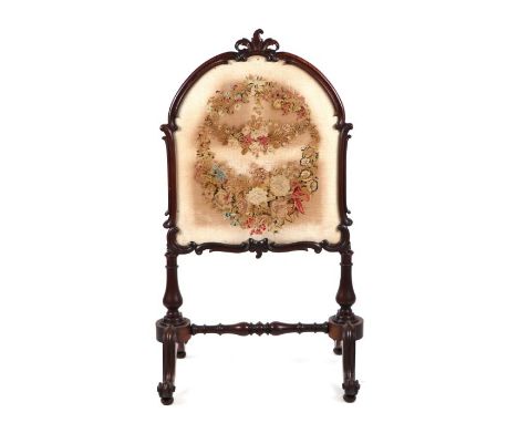 A 19th century carved mahogany firescreen with embroidered panel depicting flowers, on vase shaped supports joined by a turne