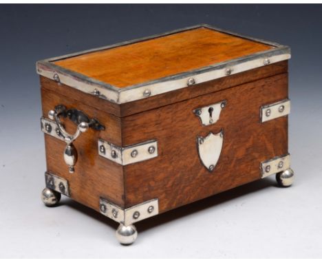 A LATE VICTORIAN OAK TEA CADDY with twin divisional interior enclosed by hinged rising lid with silver plated strap work and 