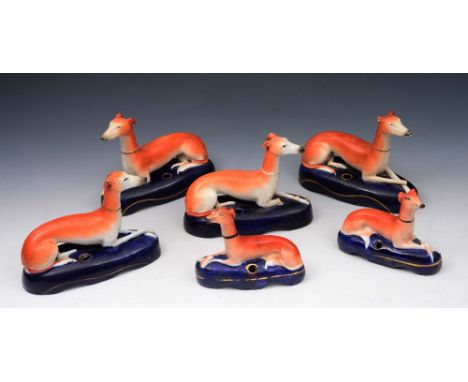 A GROUP OF SIX STAFFORDSHIRE GREYHOUND PEN HOLDERS each in a seated position on a cobalt blue base, 15cm to 10cm wide