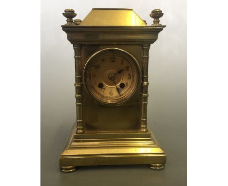 A solid brass cased mantel clock with column design, four finials to top, 21.5cm x 14.5cm x 12.5cm.