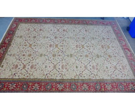 A foliate patterned carpet, the cream field within a red flowerhead border, 550 x 375cm