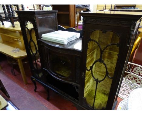 Ornately carved display cabinet having a central glazed bow front door with flanking doors over a base with shelf