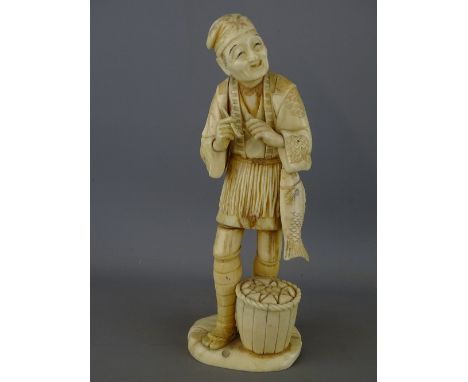 Circa 1900 carved sectional ivory Okimono depicting a smiling fisherman with pipe in his hand and a basket at his feet, the b