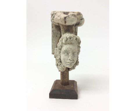 Antique ornamental stone architectural mount, with classical mask, 14.5cm high, raised on wooden stand