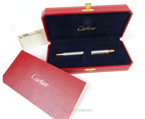 A fine, boxed, Cartier, gold plated ballpoint pen with a silver lacquered body and gold plated fittings, engraved 'Cartier' a