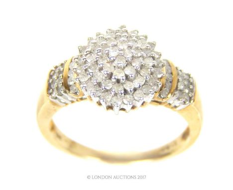 A 9 ct yellow gold and diamond cluster ring, centrally set with a cluster of four radiating rows of small, claw- set, brillia