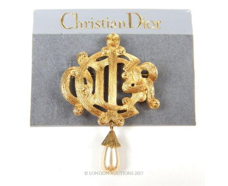 A Christian Dior costume jewellery brooch set in gilt metal and composed of an intertwined 'C' and 'D' in a textured finish a