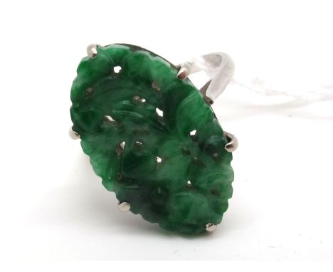 A Carved Oval Jade Panel Ring, claw set between plain shoulders, stamped "18ct" (finger size O1/2). 