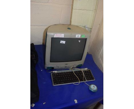 A 1998 Apple iMac computer monitor with matching keyboard and round mouse