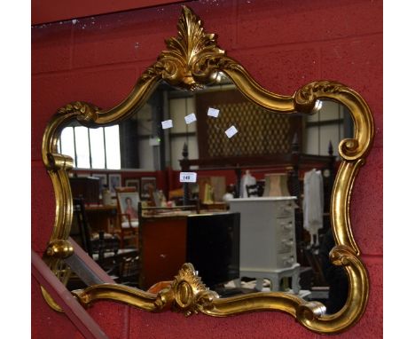 A contemporary gilt framed wall mirror, shaped rectangular plate, cresting frame carved with C-scrolls. 70cm x 80cm.