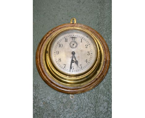 A brass ship's clock, Barkers, Kensington, on oak roundel