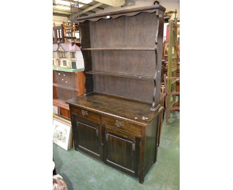 An oak dresser, shaped uprights, two short drawers over two fielded panel doors to base. 191cm high x 122cm wide x 51cm deep.