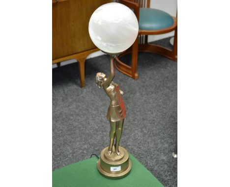 An Art Deco style table lamp in the form of a young girl holding aloft a opaque globe.